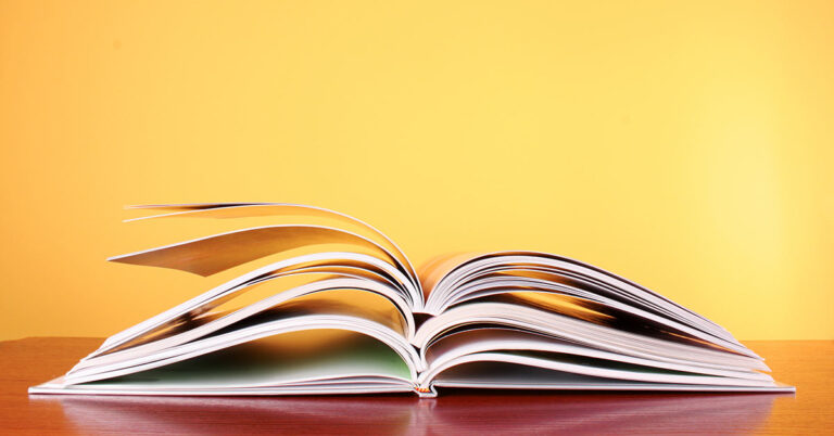 Offenes Buch auf roter Ablage, vor gelbem Hintergrund; Expose