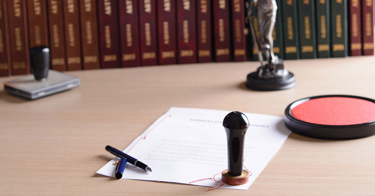 Auf einem Tisch beim Notar liegt ein Immobilienkaufvertrag, mit Stift zum Unterschreiben und Stempel | Notartermin
