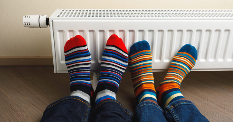 legs with colorful socks in front of heating radiator; Neues GEG